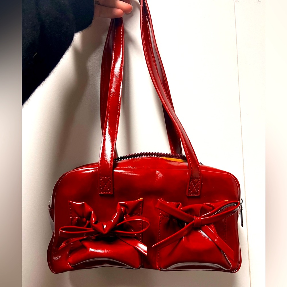 Red pleather bow tie shoulder purse. Front pockets and inside pockets. Shiny red